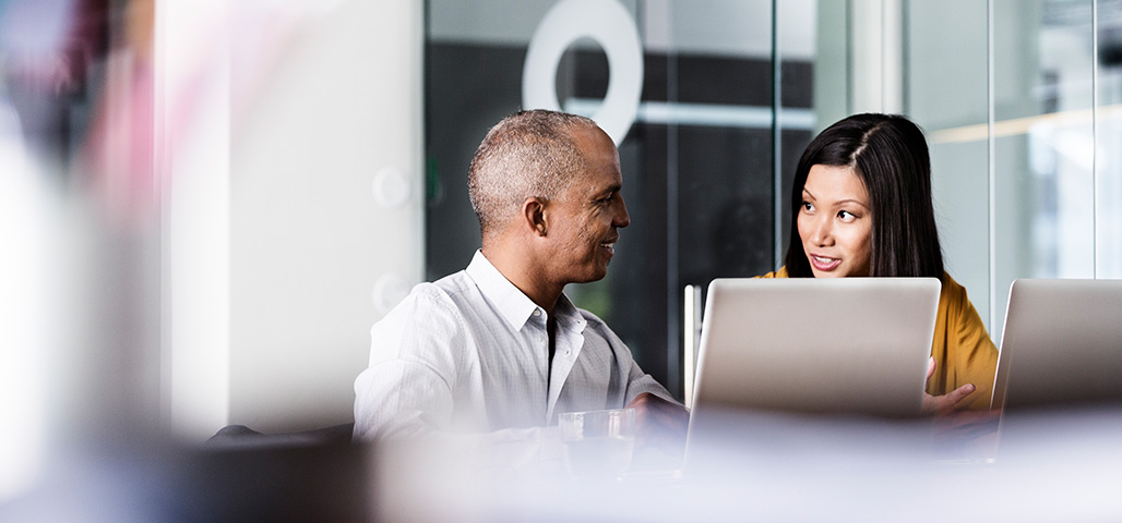 A man and a woman sitting next to each other in front of a computer. 